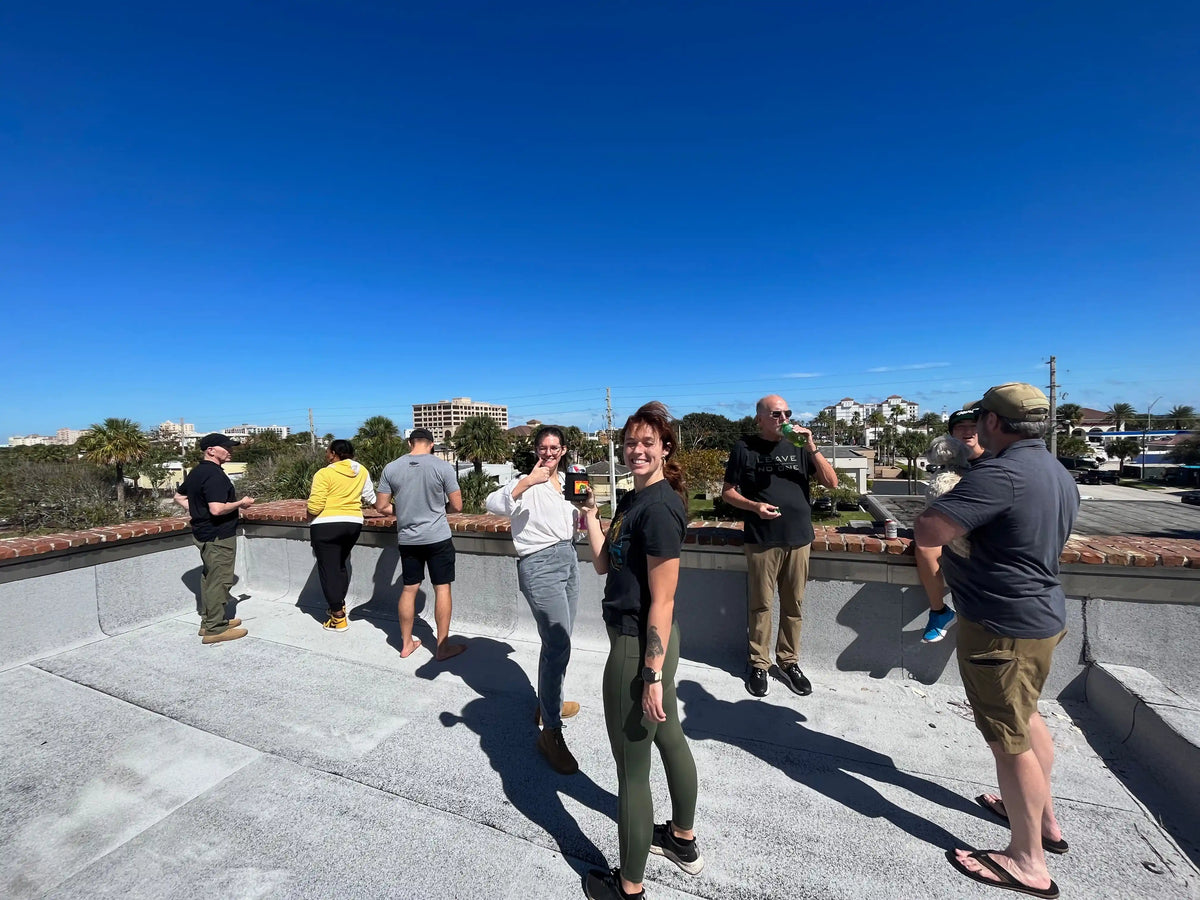 Group of people enjoying sunny rooftop gathering, GORUCK community, city skyline in background