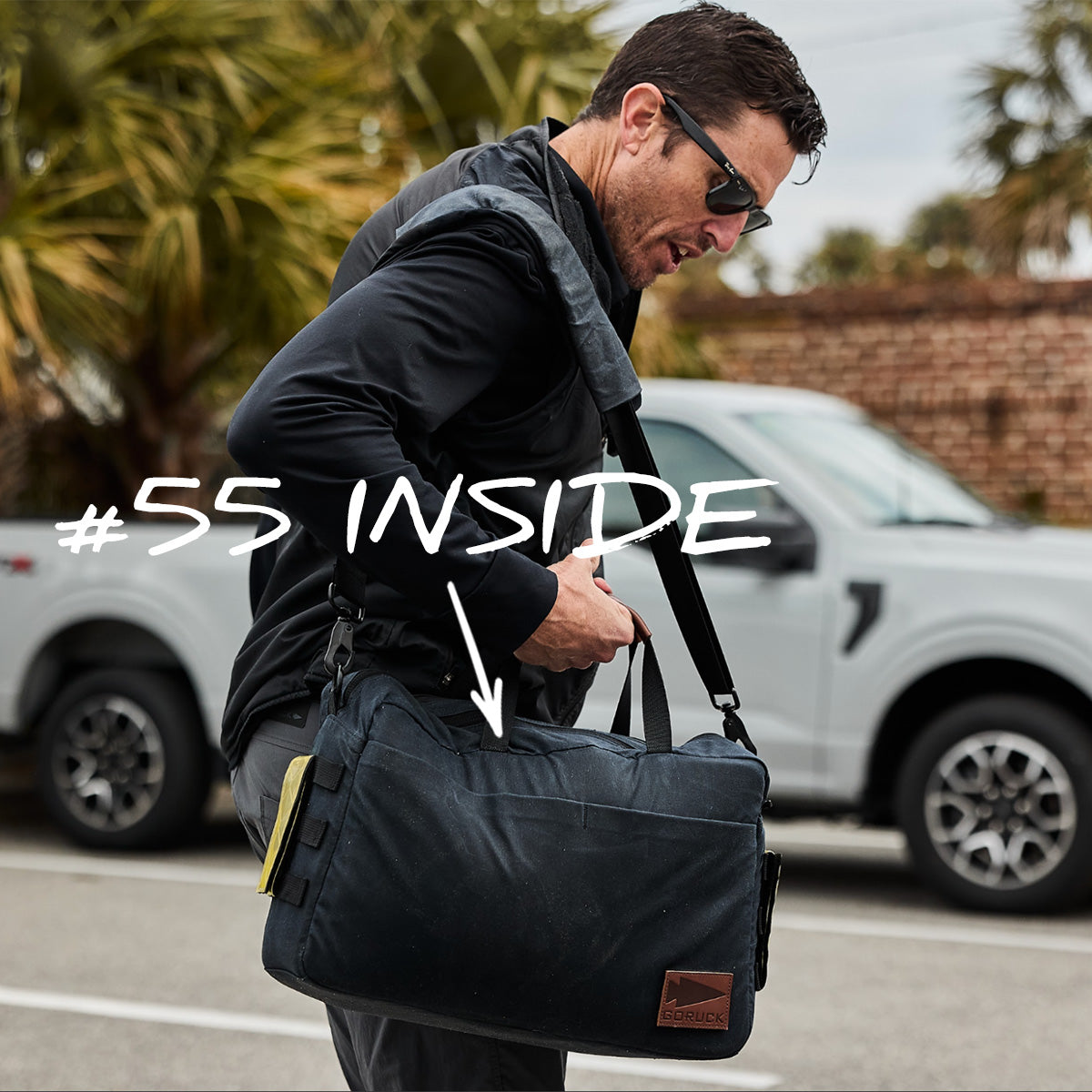 Man wearing sunglasses carries a black duffel bag with “55 INSIDE” text and arrow pointing to the bag.