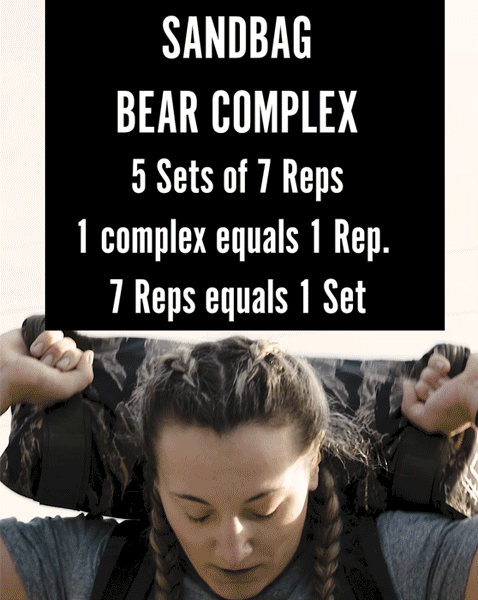Woman lifting a sandbag with workout instructions shown: 5 sets of 7 reps for the Sandbag Bear Complex.