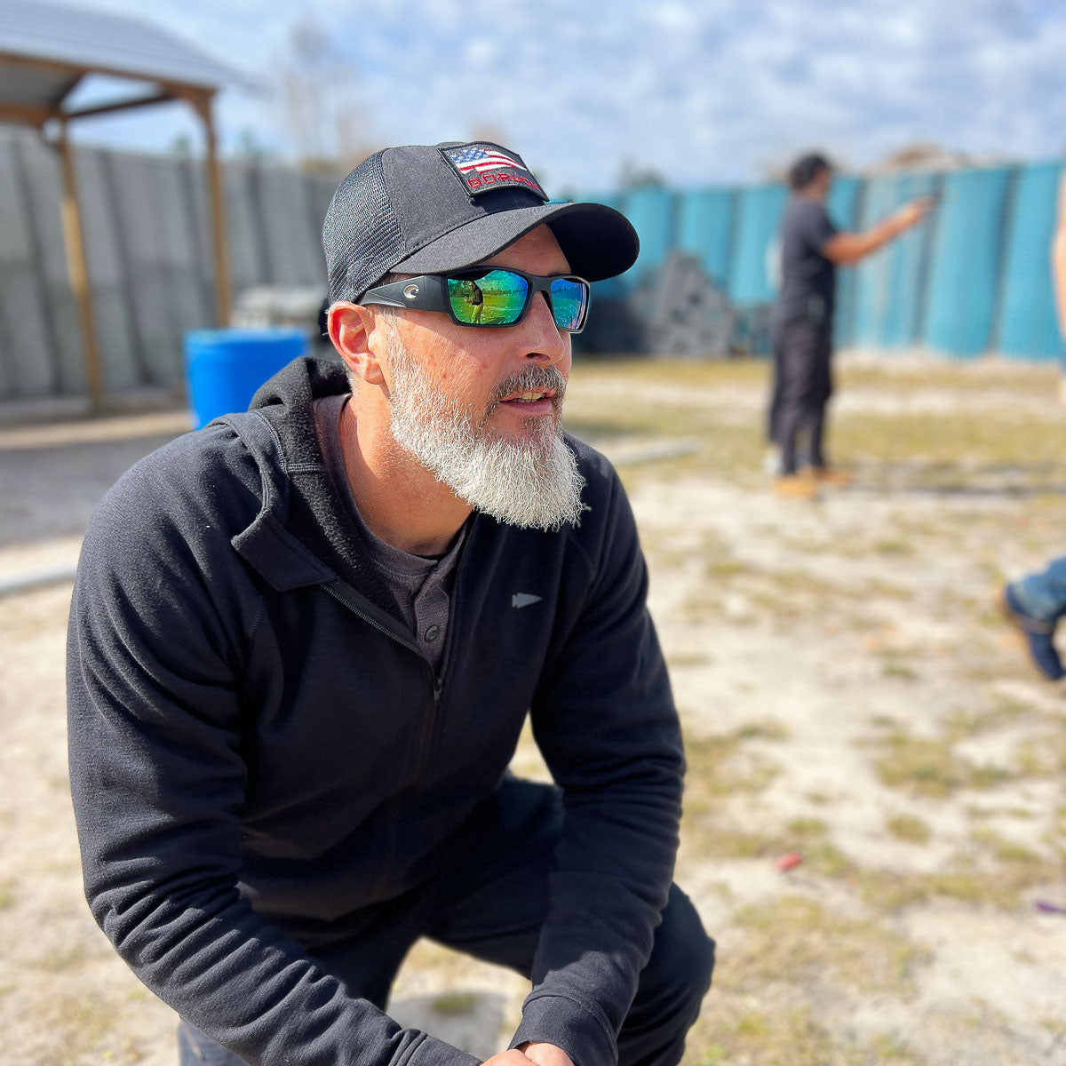 Man in black GORUCK Cadre hat and sunglasses outdoors at rucking training event