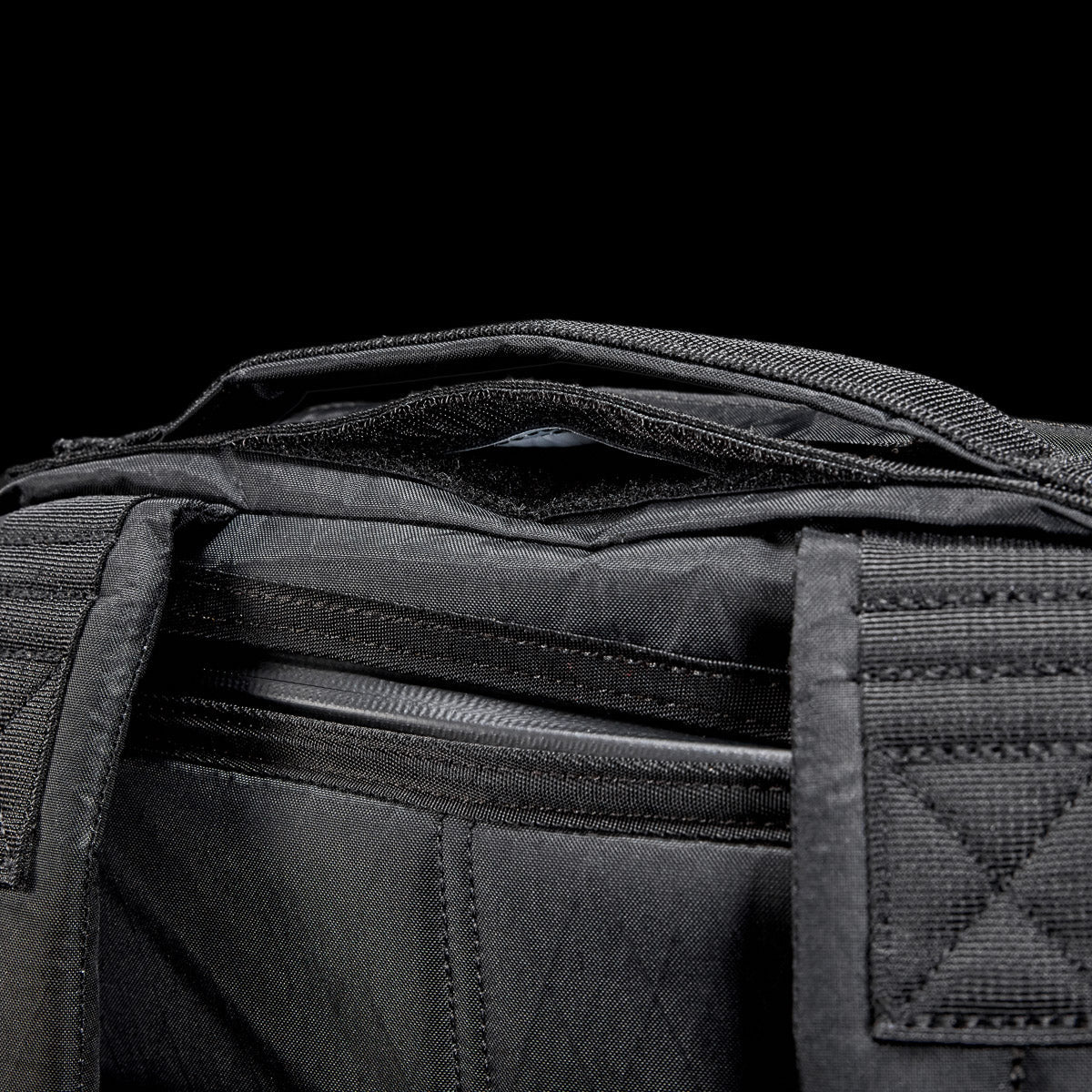 GORUCK black ruck backpack top handle and zipper detail against black background