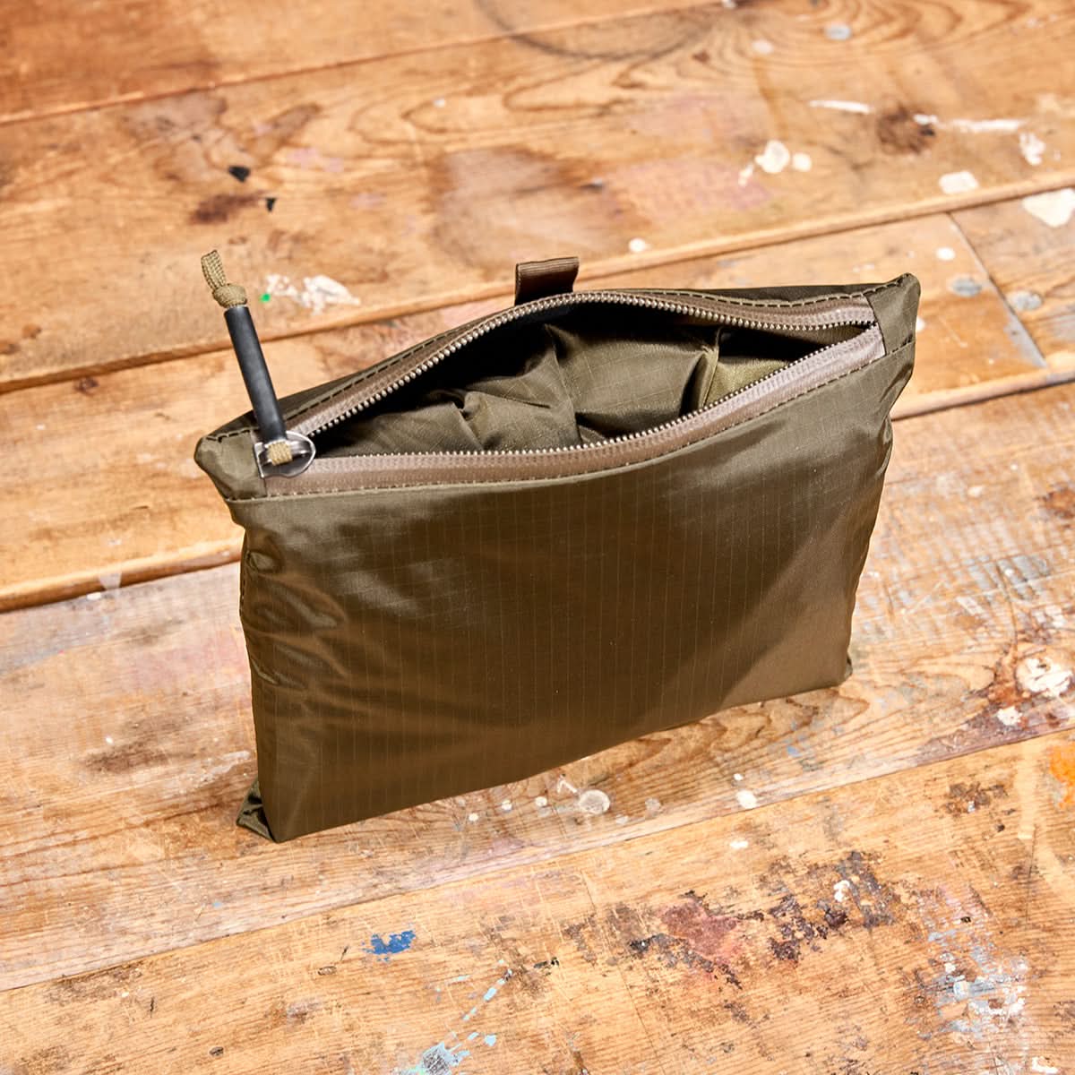 GORUCK packable ranger green zippered pouch on distressed wooden surface