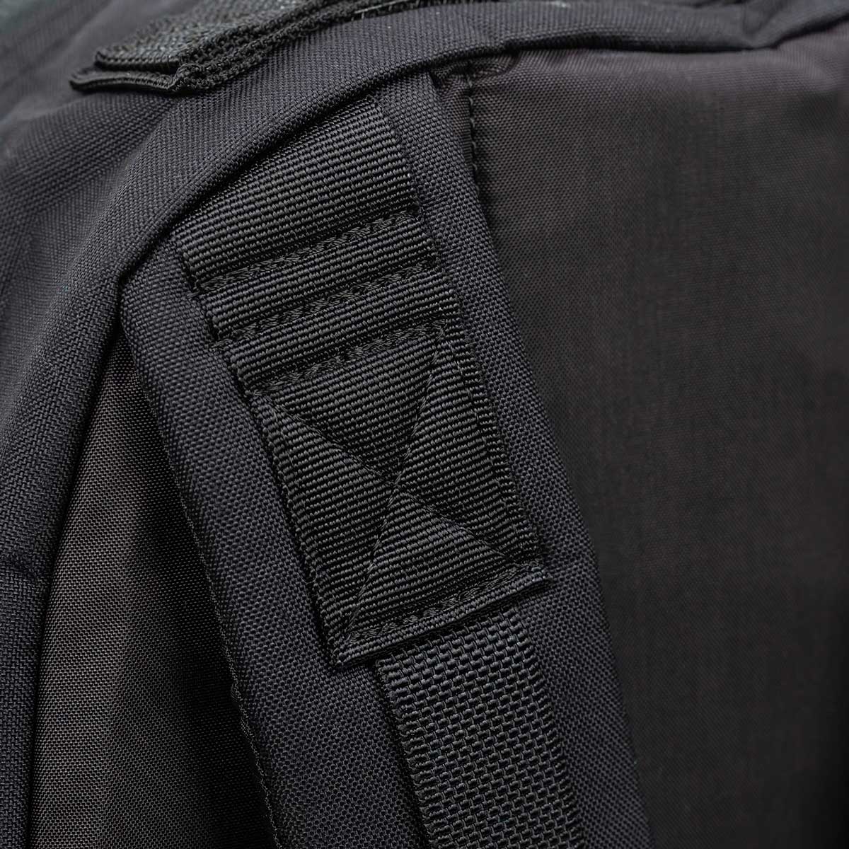 Close-up of a black backpack strap with reinforced stitching and durable fabric.