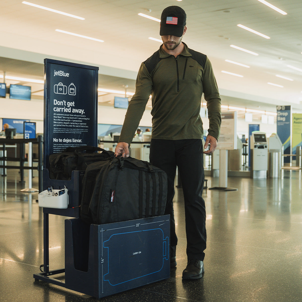 A man checks his carry-on bag size at a jetBlue baggage sizer in an airport terminal.