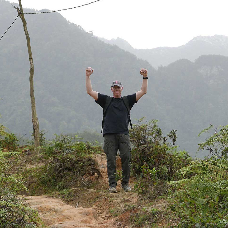 A man standing on a trail with his arms raised.