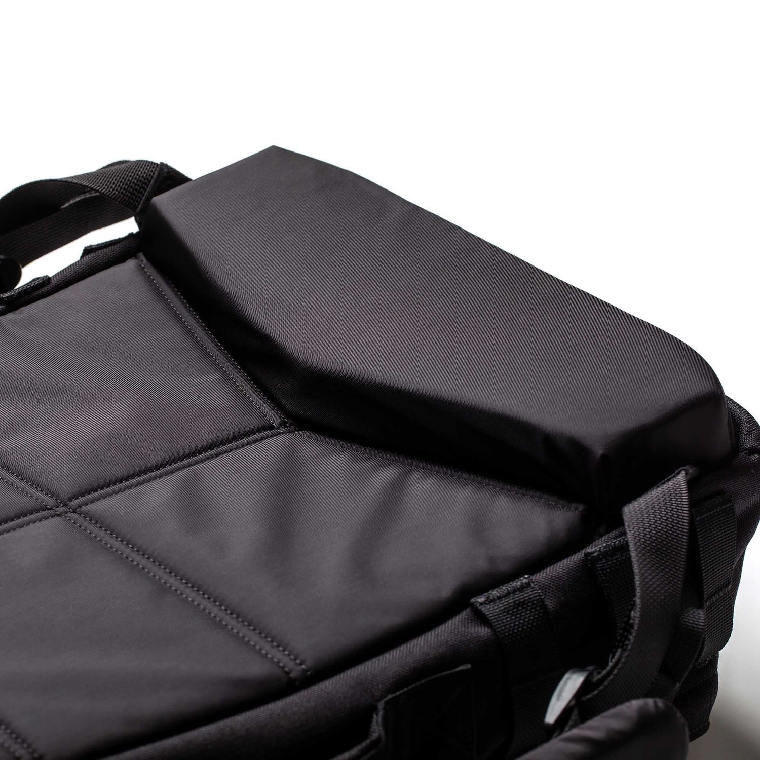Close-up of the Rucker 5.0, a black padded rucksack with stitched sections and black straps, perfect for rucking, on a white background.