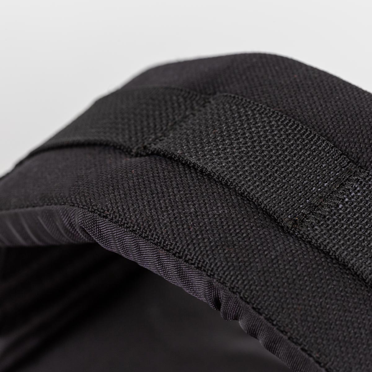Close-up of a black fabric strap and padded material, possibly part of a bag or backpack.