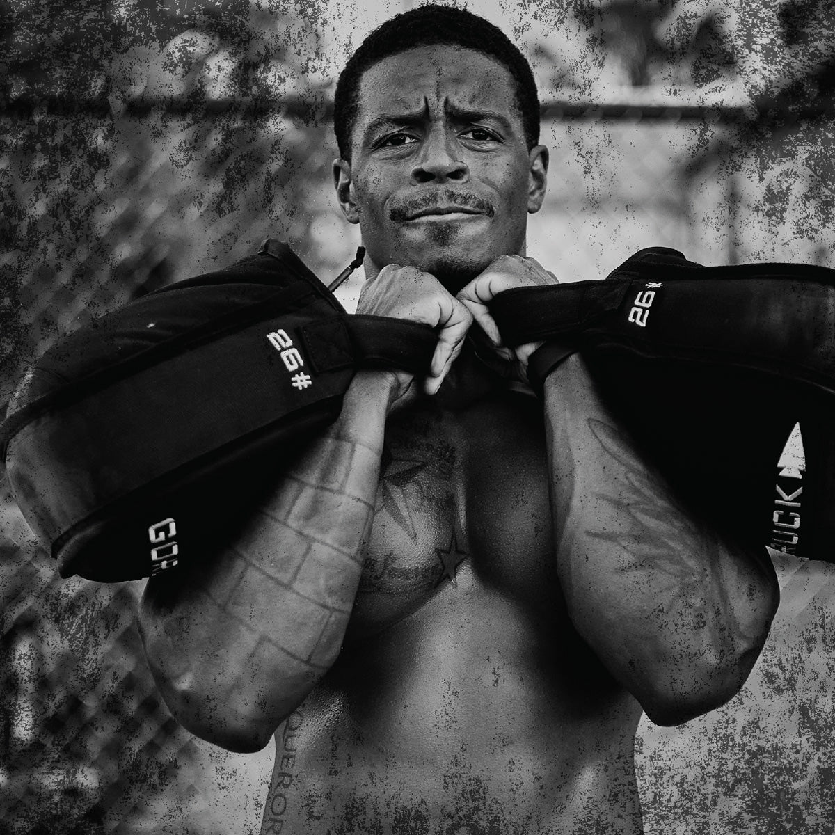 A shirtless man lifts weights outdoors, looking determined, with a gritty, textured black-and-white effect.
