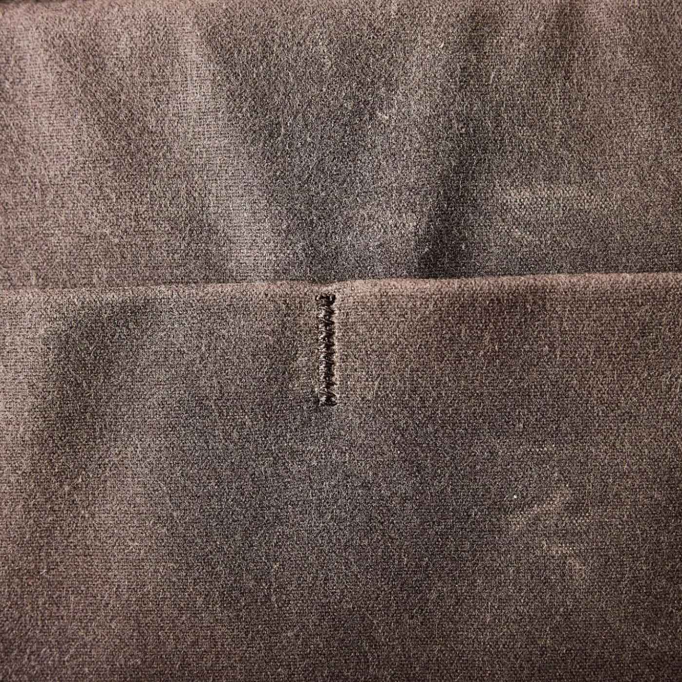 Close-up of grey fabric with a small, neat vertical stitch in the center.