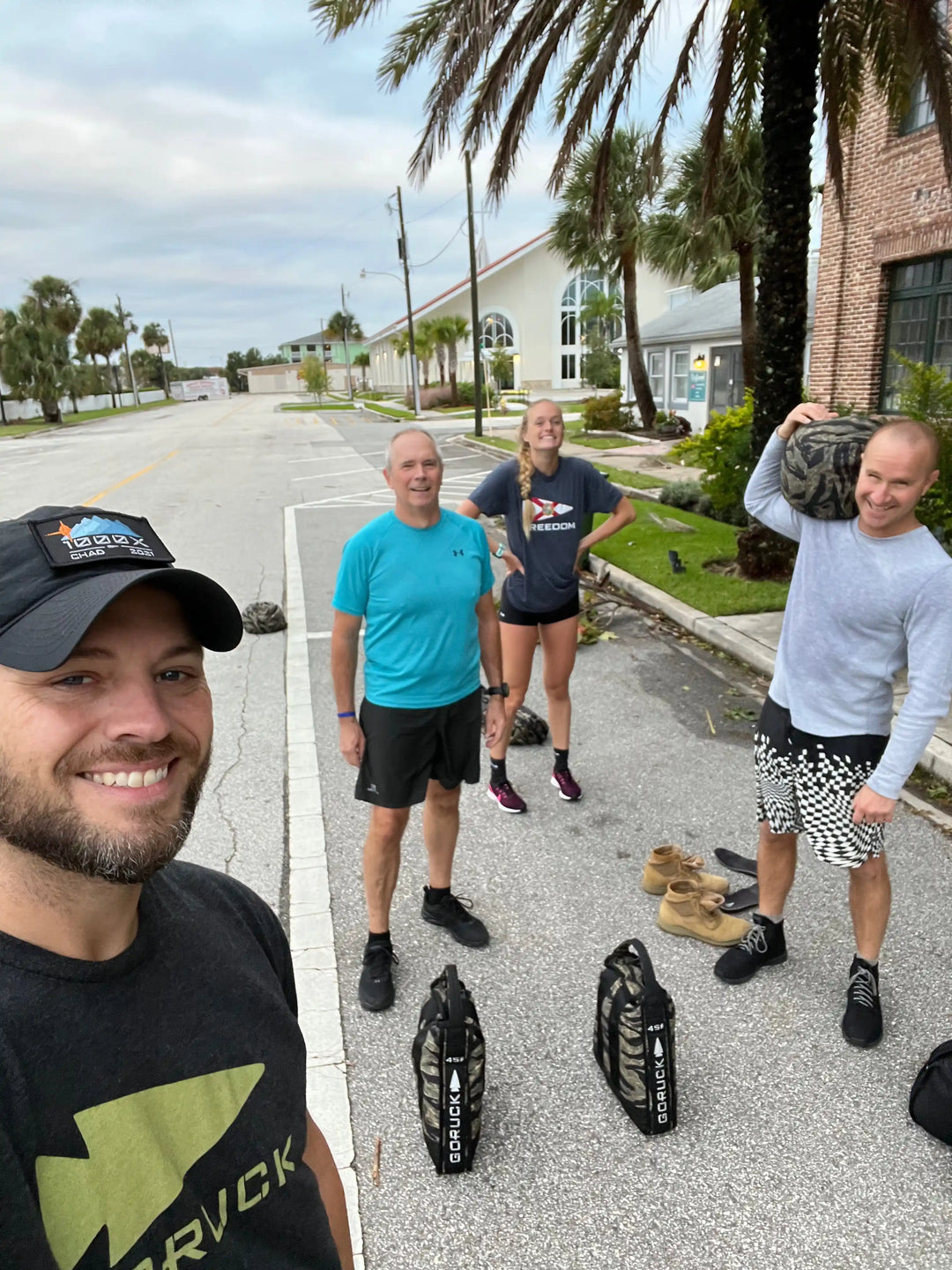 Group of four people outdoors with GORUCK gear and sandbags, ready for rucking workout