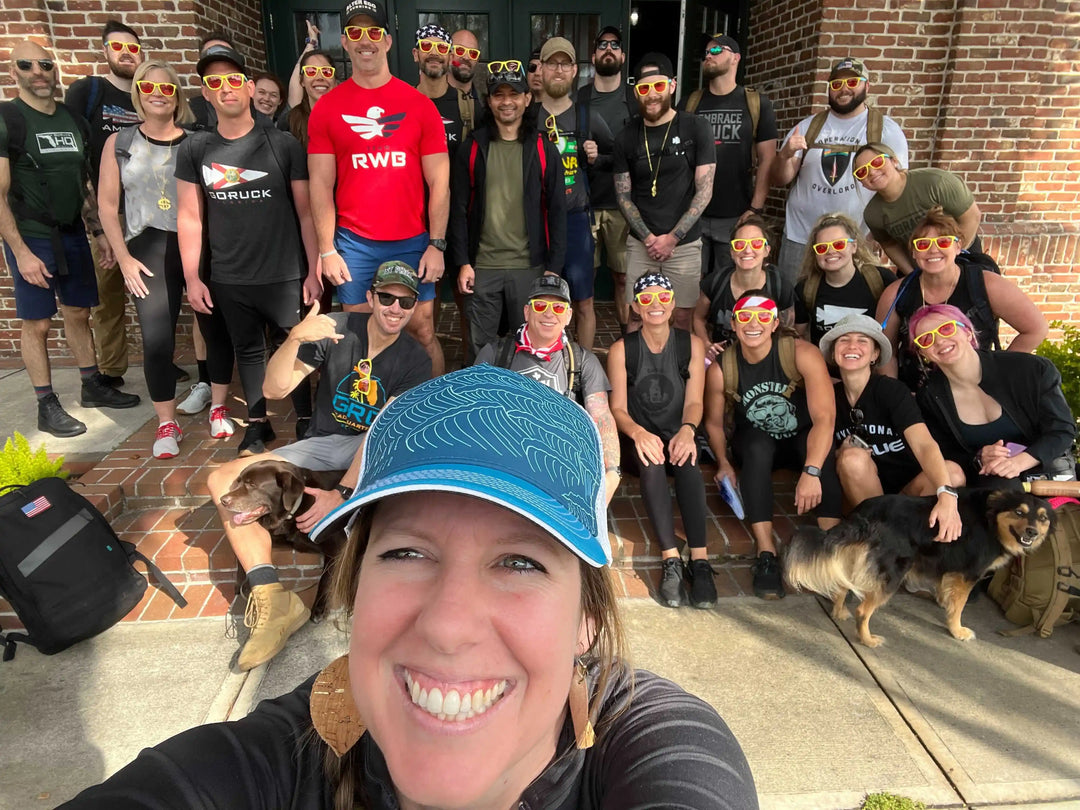 GORUCK team group photo outside, smiling with rucking gear and dogs, wearing sunglasses.