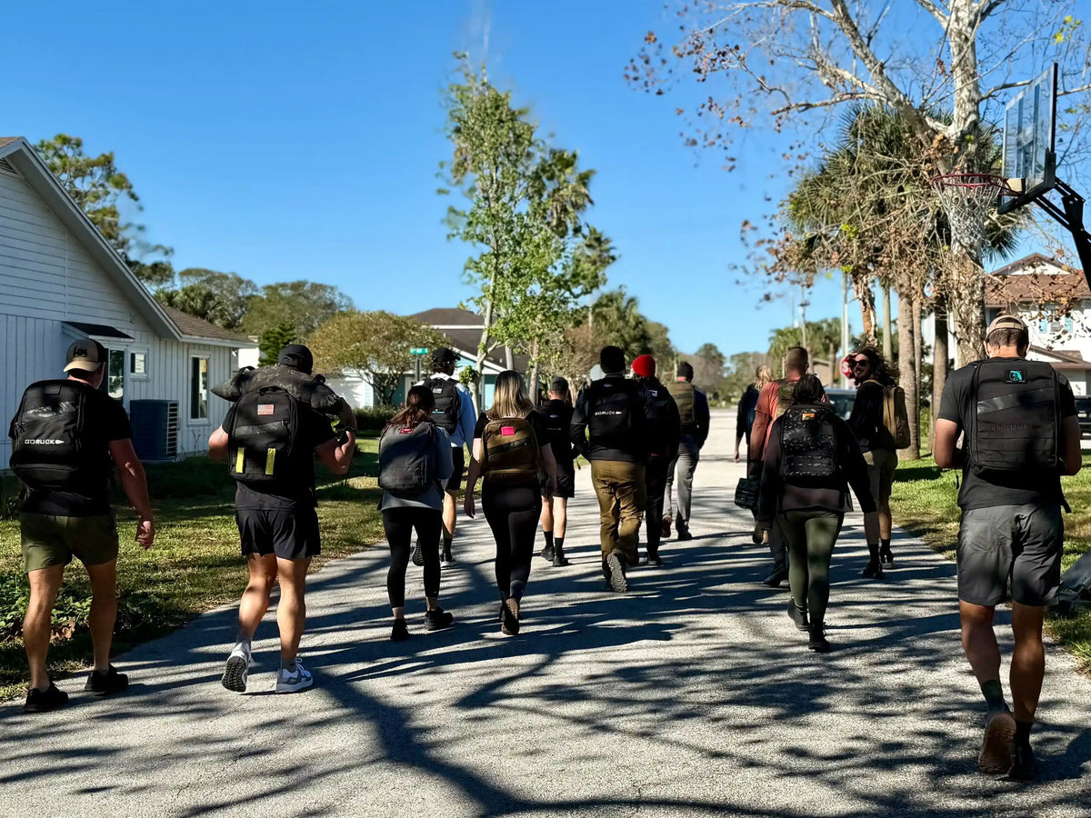 Group of people rucking outdoors with GORUCK backpacks on a sunny neighborhood street