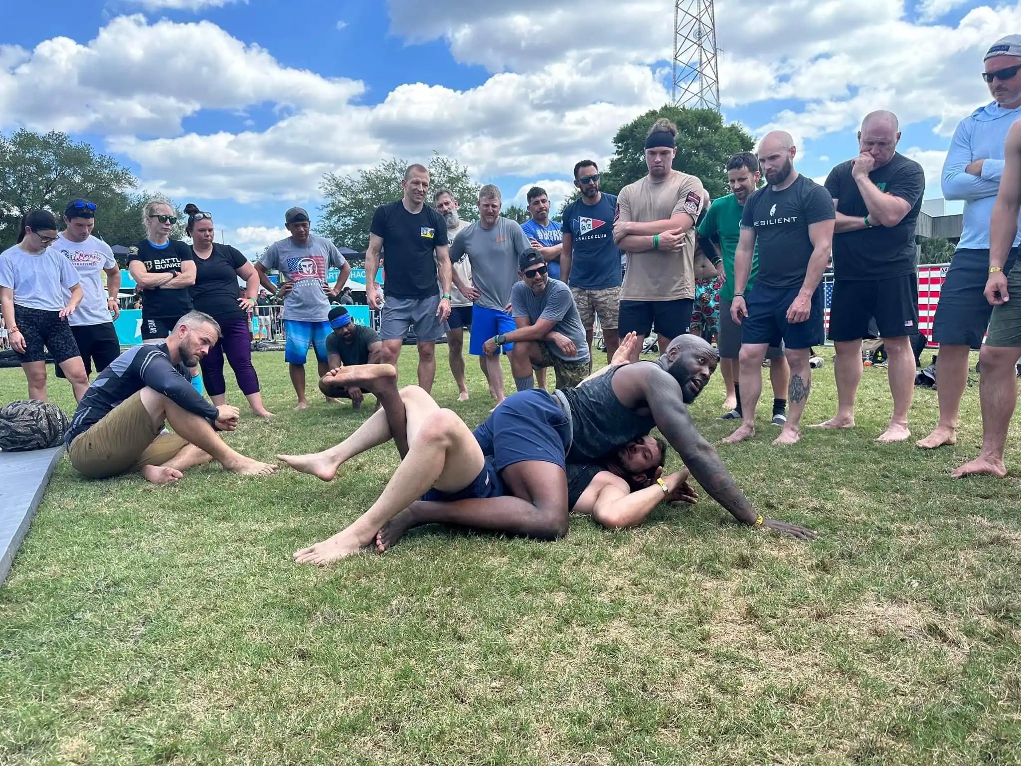 GORUCK outdoor training event with group watching ground grappling demonstration on grass
