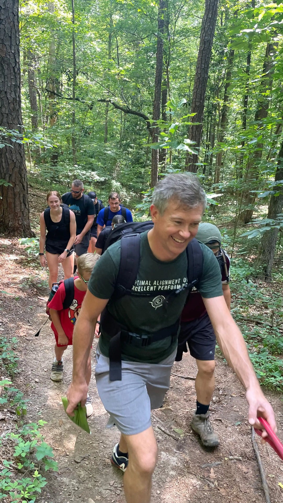 GORUCK group rucking with backpacks on forest trail, highlighting outdoor teamwork and training