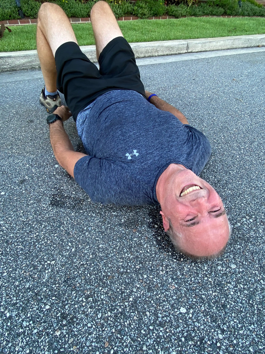 Man in workout clothes smiling while exercising outdoors on pavement, GORUCK fitness training