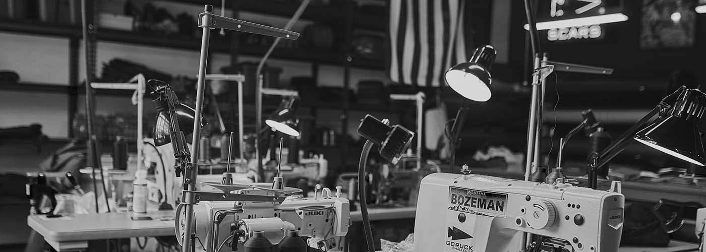 Sewing machines in a workshop with lamps and shelves in the background.