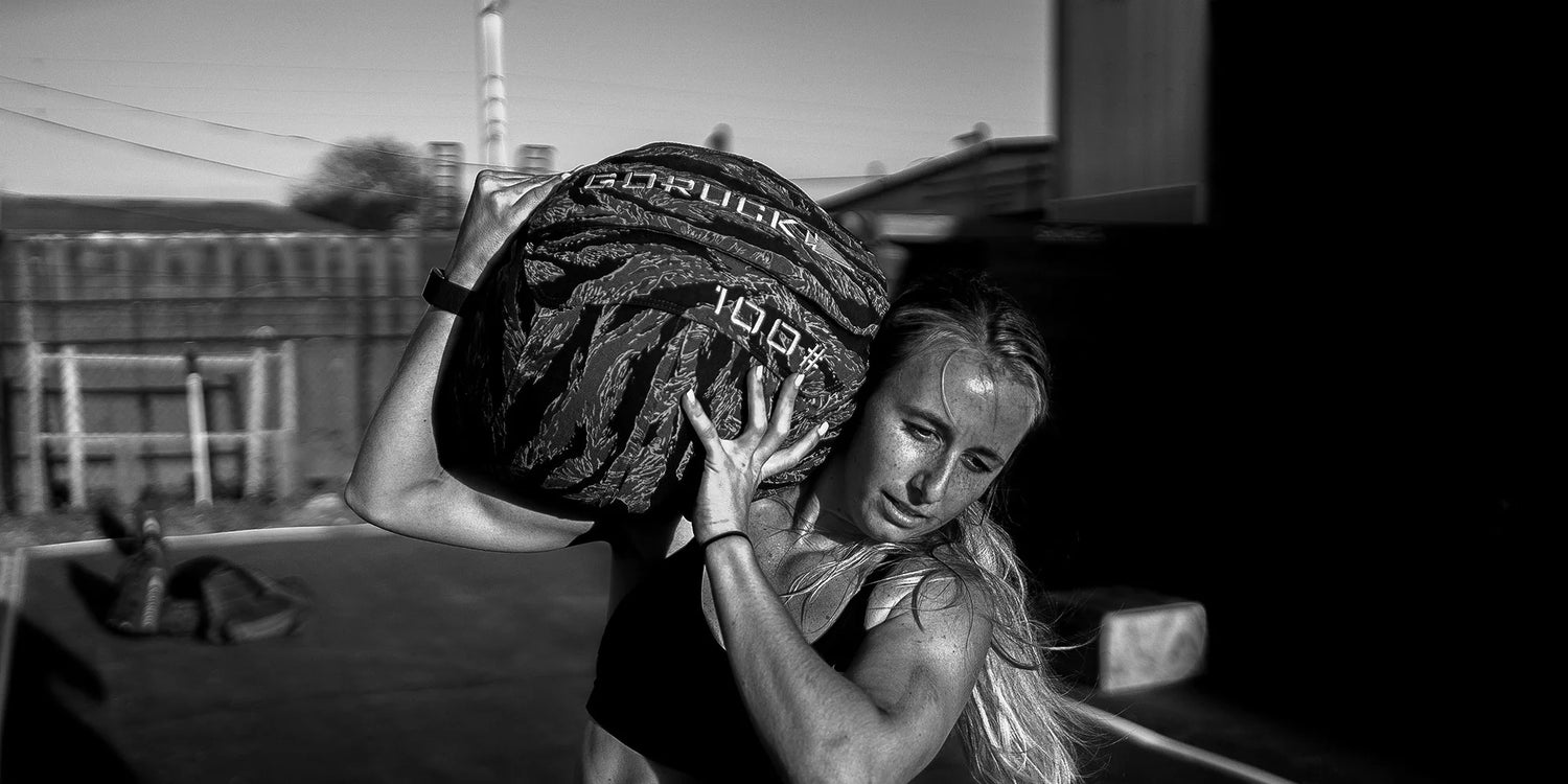 Woman lifting a heavy sandbag labeled 