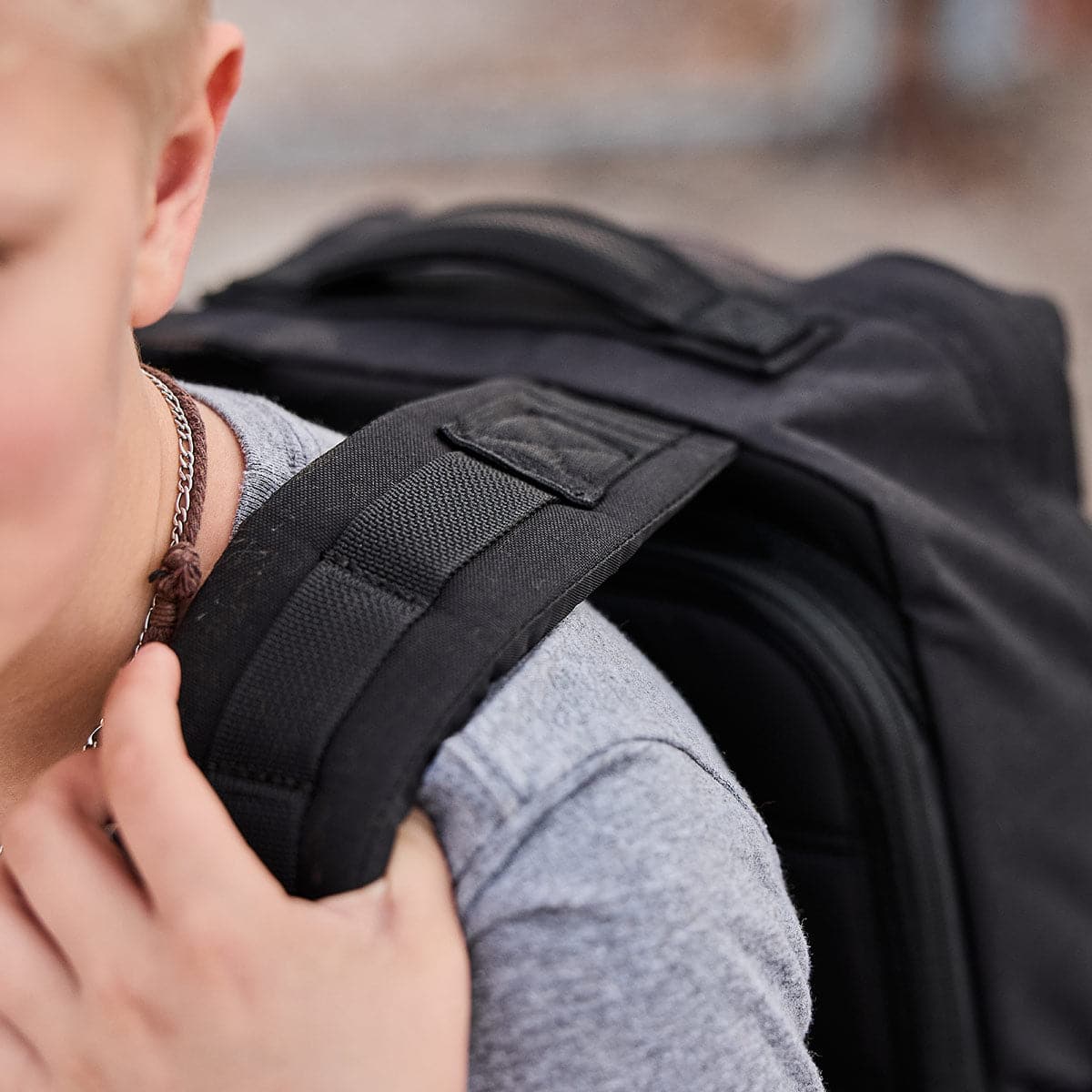 A person dressed in a gray shirt is carrying the durable GORUCK KR1 book bag over their shoulder.