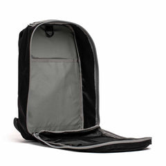 A black backpack with its main compartment fully unzipped, showing a spacious gray interior and mesh pocket.