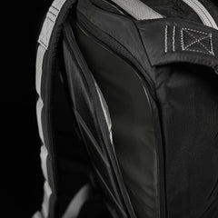 Close-up of a black backpack, showing an open zippered compartment and padded shoulder straps.
