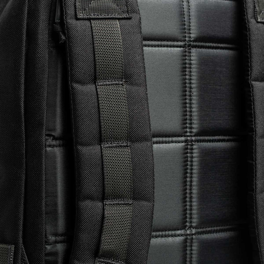 A detailed view of the GR2 black backpack by GORUCK showcases its padded straps and quilted back panel design, drawing inspiration from Special Forces medical packs and supported by the Scars Lifetime Guarantee.