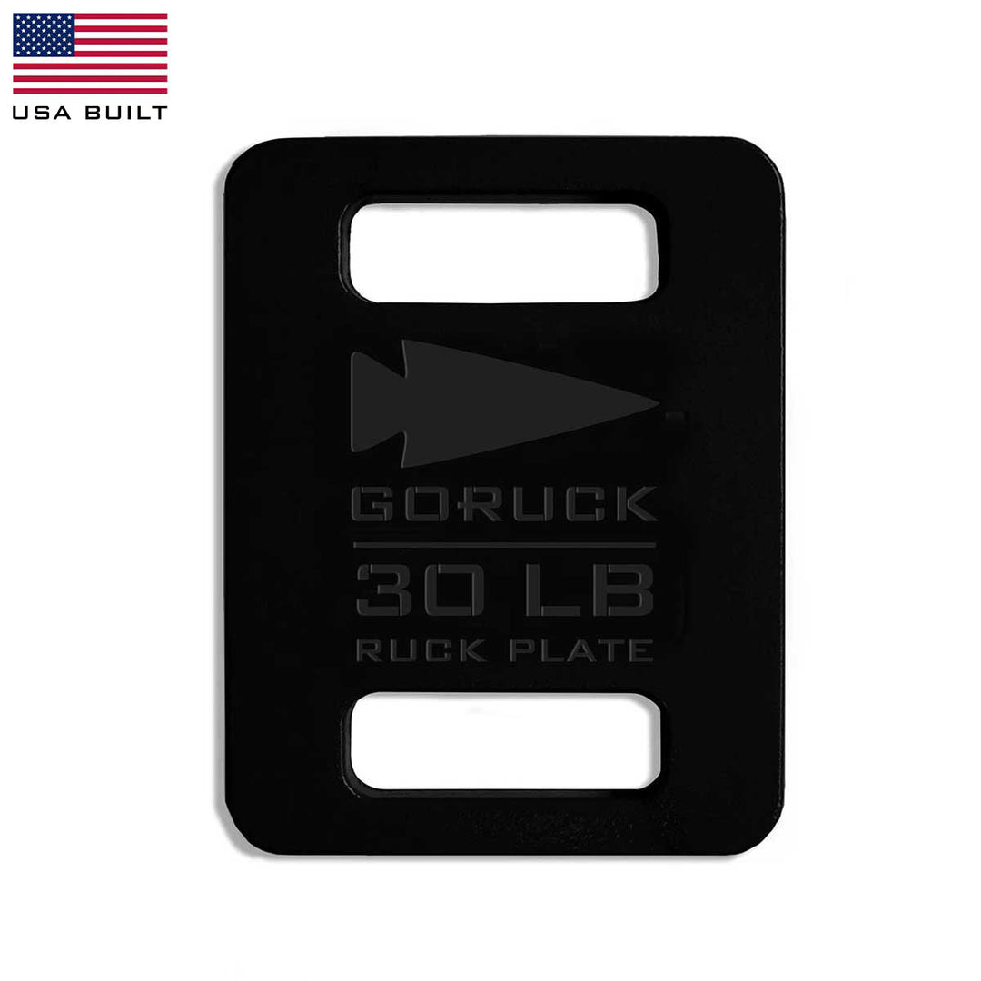 The GORUCK Ruck Plates - 30 lb, in black, offer convenient cutout handles and are designed to fit perfectly in your Rucker or any Ruck Plate Carrier. They feature a sleek American flag in the corner, symbolizing quality and endurance for your toughest challenges.