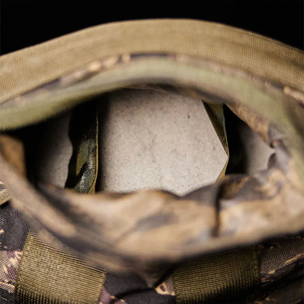 A close-up of a camouflage-patterned bag showing a white object inside the main compartment.