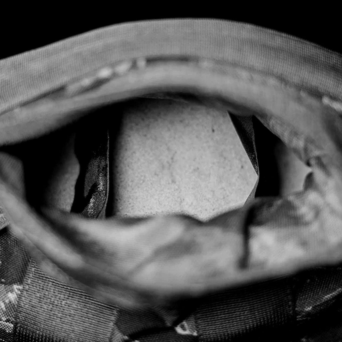 A close-up of a partially open backpack in black and white, showing the inside fabric and zipper.