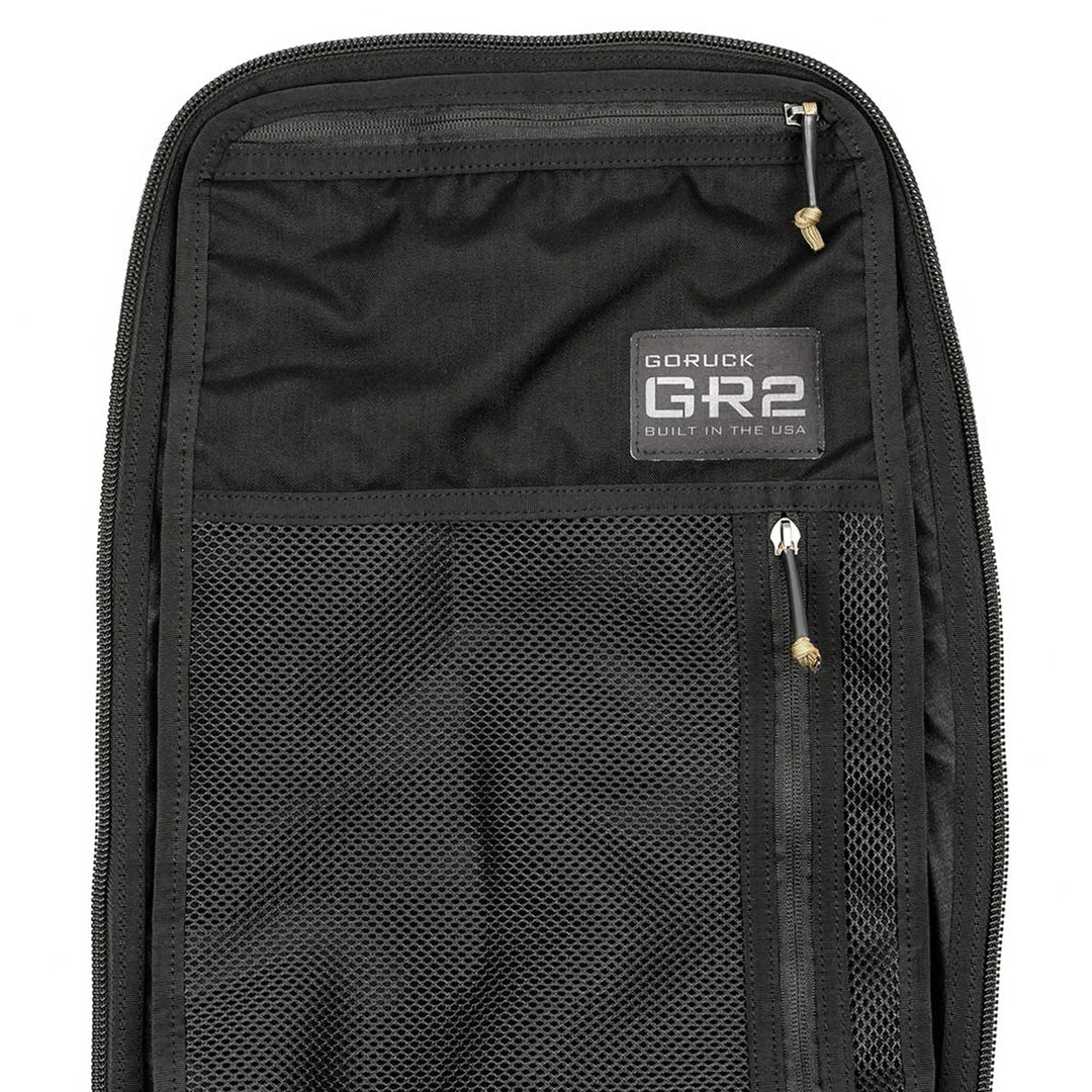 Black backpack featuring a mesh pocket and a tag labeled "GORUCK GR2, Built in the USA." Drawing inspiration from Special Forces medical packs, this GR2 backpack by GORUCK also comes with the Scars Lifetime Guarantee for unmatched durability.