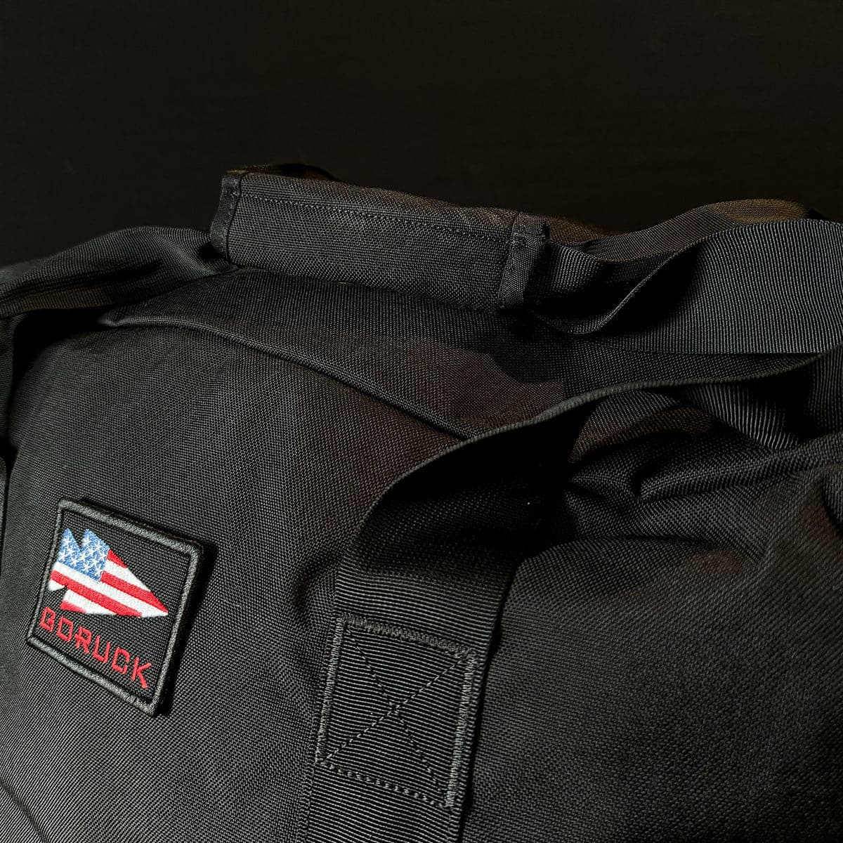 A dark-themed Kit Bag - 84L by GORUCK, featuring an American flag patch and 