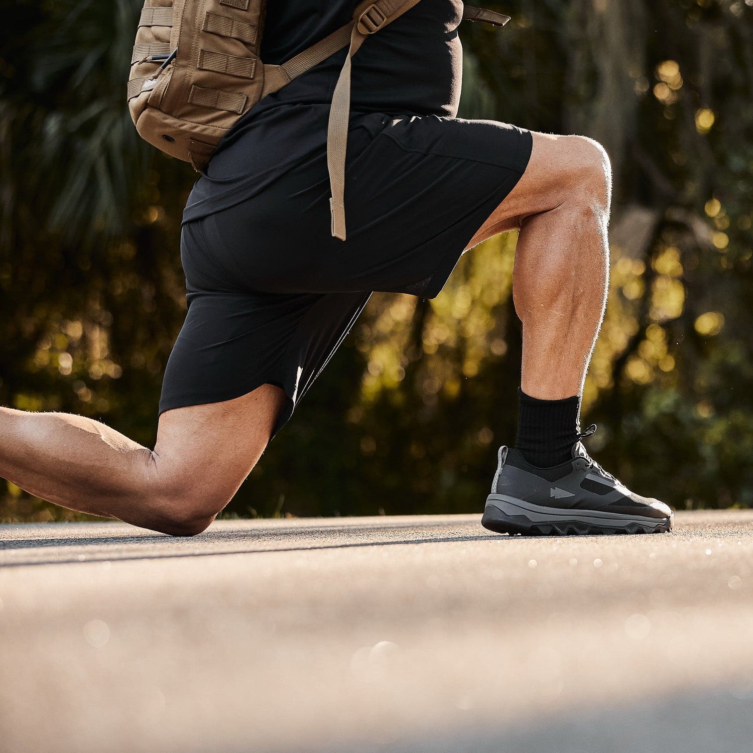 Man performing outdoor lunge in GORUCK gear and backpack, promoting rucking fitness.