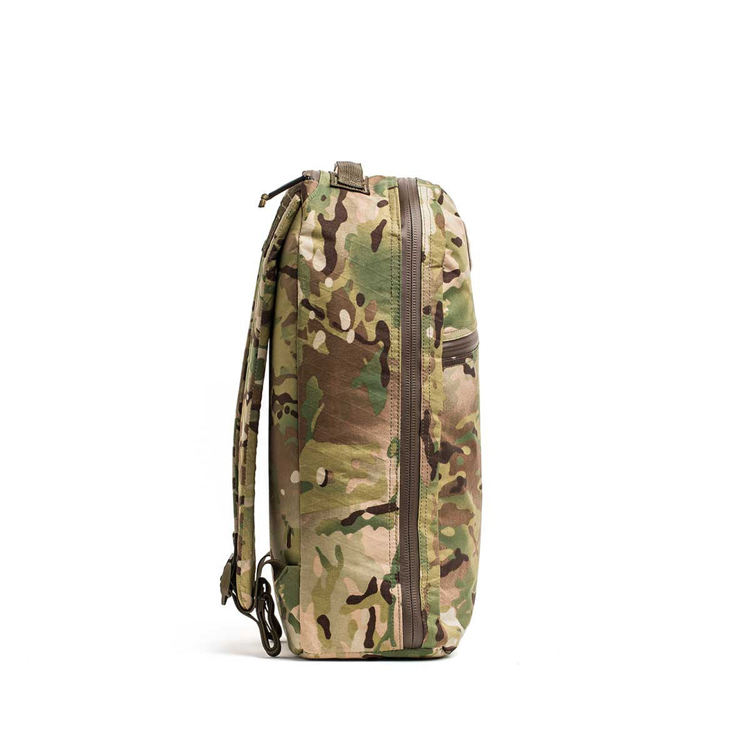 Side view of the GORUCK Bullet X-PAC backpack featuring a weatherproof camouflage design, zipper pocket, and adjustable shoulder straps.
