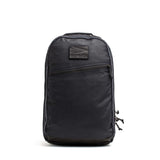 The GORUCK Bullet Ruck - Heritage Waxed Canvas - 18L, crafted from black waxed canvas and featuring a front zipper pocket with a signature GORUCK logo patch, is shown against a white background—making it the ideal daypack for your daily adventures and travel.