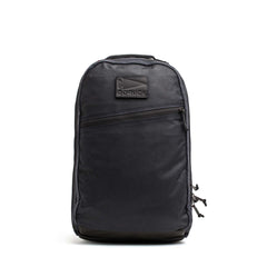 The GORUCK Bullet Ruck - Heritage Waxed Canvas - 18L, crafted from black waxed canvas and featuring a front zipper pocket with a signature GORUCK logo patch, is shown against a white background—making it the ideal daypack for your daily adventures and travel.