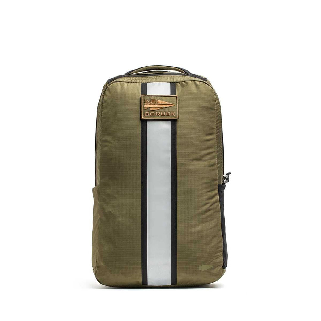 The olive green Basic Rucker® backpack features a black and white vertical stripe and a brown front logo patch—ideal for versatile weighted rucking.