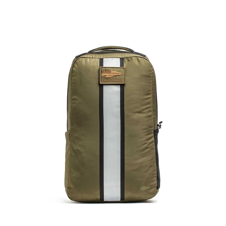 The olive green Basic Rucker® backpack features a black and white vertical stripe and a brown front logo patch—ideal for versatile weighted rucking.