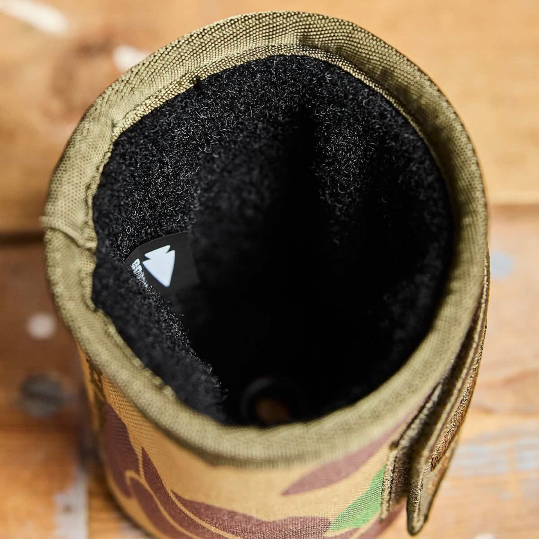 Top view of the GORUCK Ballistic Beer Jacket, an empty camouflage koozie made from durable 1000D CORDURA with a black interior, resting on a wooden surface.