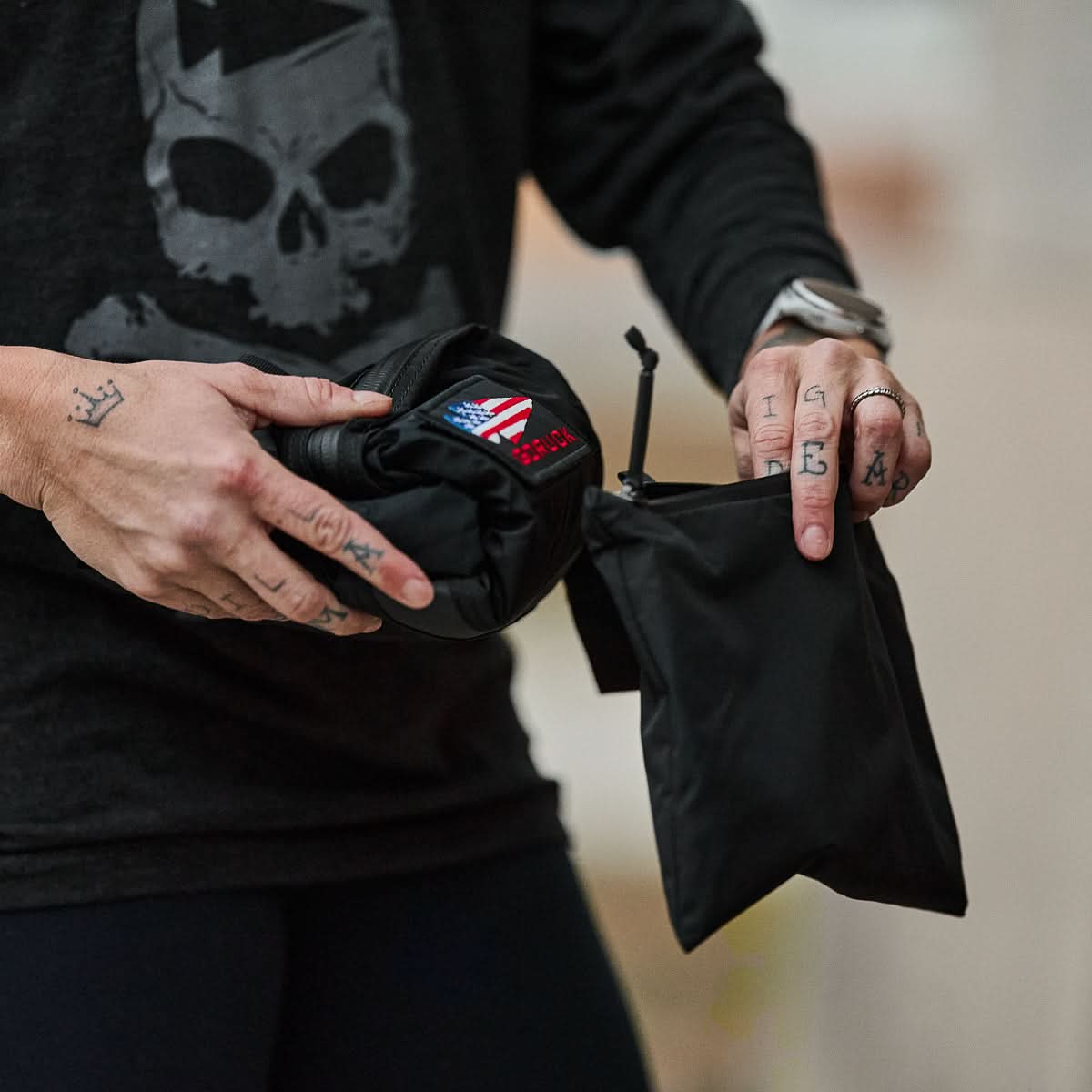 Person holding a compact black GORUCK packable bag with American flag patch