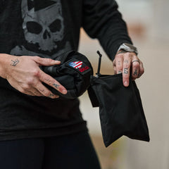 Person holding a compact black GORUCK packable bag with American flag patch