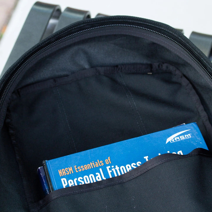 GORUCK rucksack open showing NASM Essentials of Personal Fitness Training book inside pocket