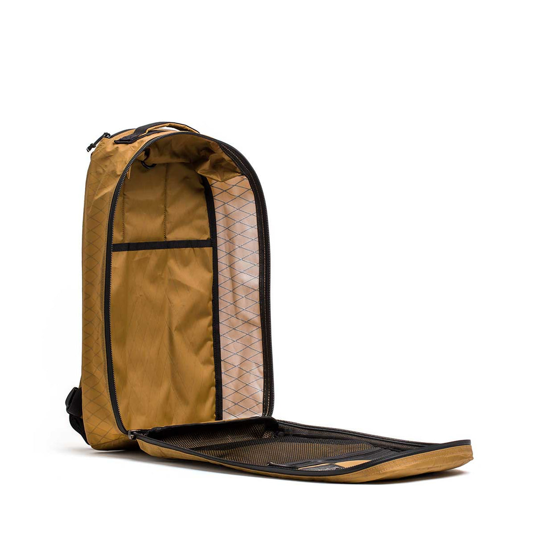 The GORUCK Bullet X-PAC backpack in tan is shown upright with its weatherproof main compartment unzipped and open.
