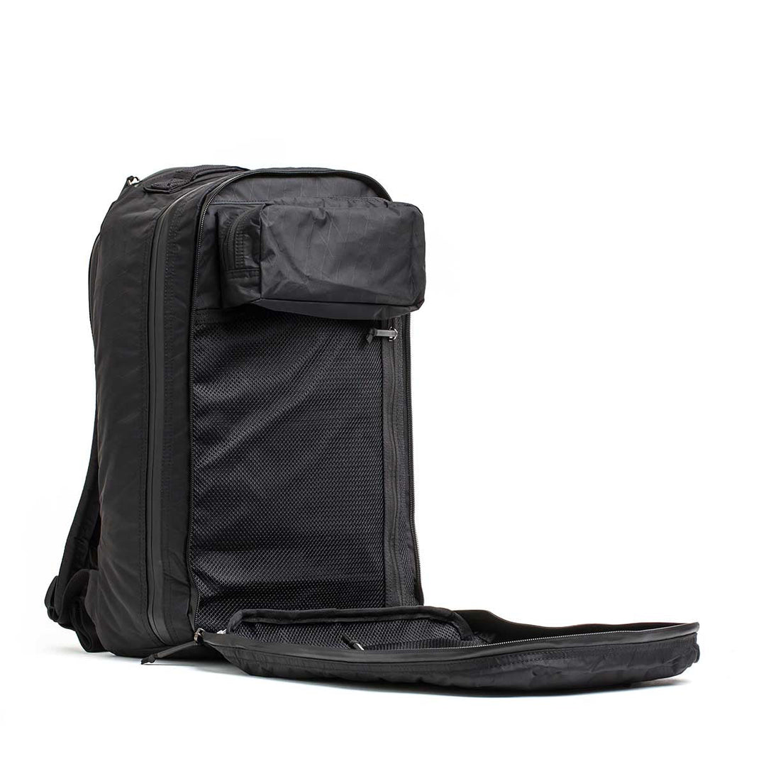 The Double Compartment Bullet Ruck - XPAC stands upright with its front unzipped, showing mesh pockets and a bombproof laptop compartment for secure travel.