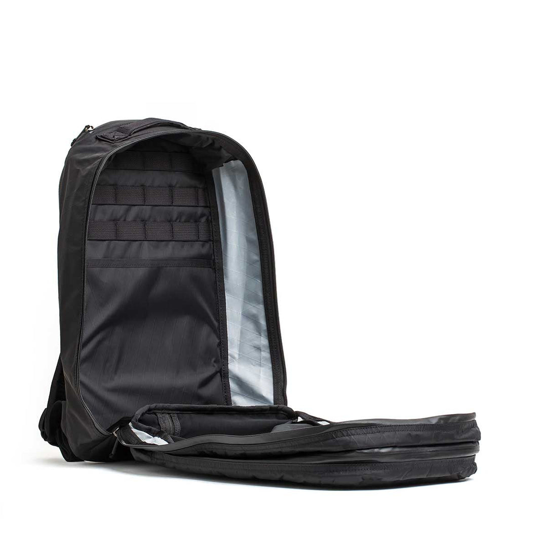 The Double Compartment Bullet Ruck - XPAC stands upright with its main compartment unzipped, showing organized interior pockets and an ultra-durable laptop compartment.
