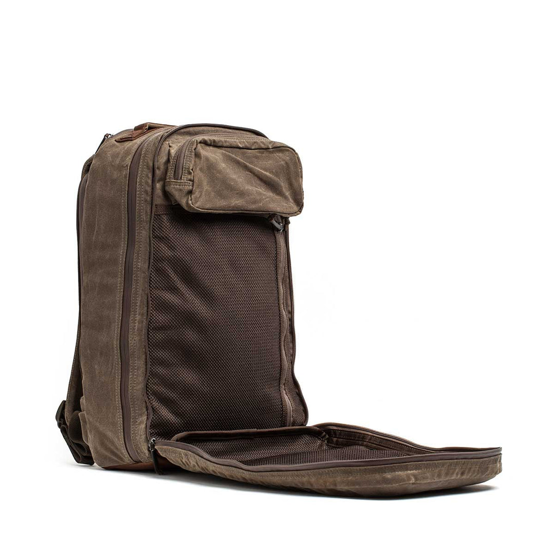 The GORUCK Bullet Ruck - Heritage Waxed Canvas - 18L features a brown waxed canvas design, a front pocket with mesh compartment, and a spacious interior—perfect for hands-free travel.