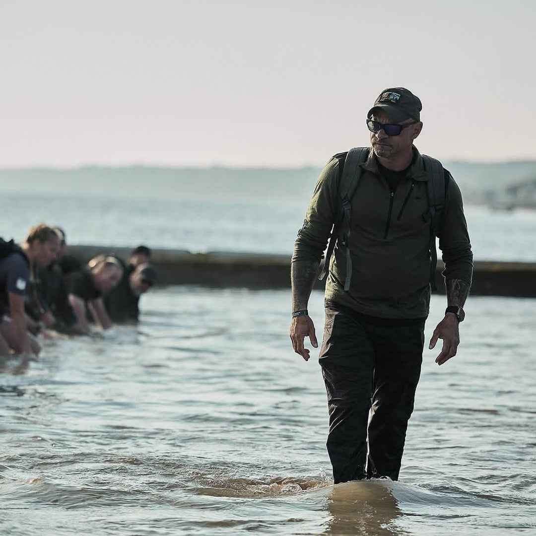 Man in GORUCK gear leading group rucking through water during outdoor endurance event