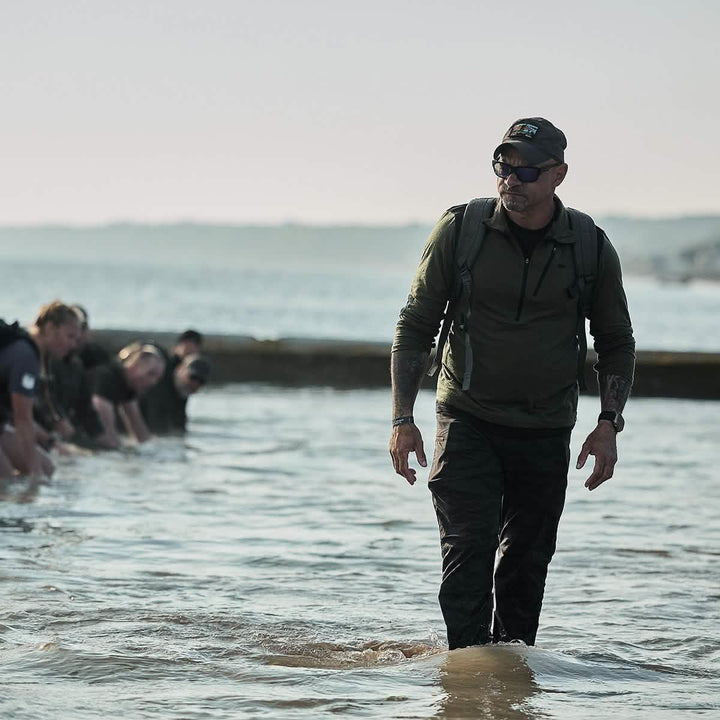 Man in GORUCK gear leading group rucking through water during outdoor endurance event