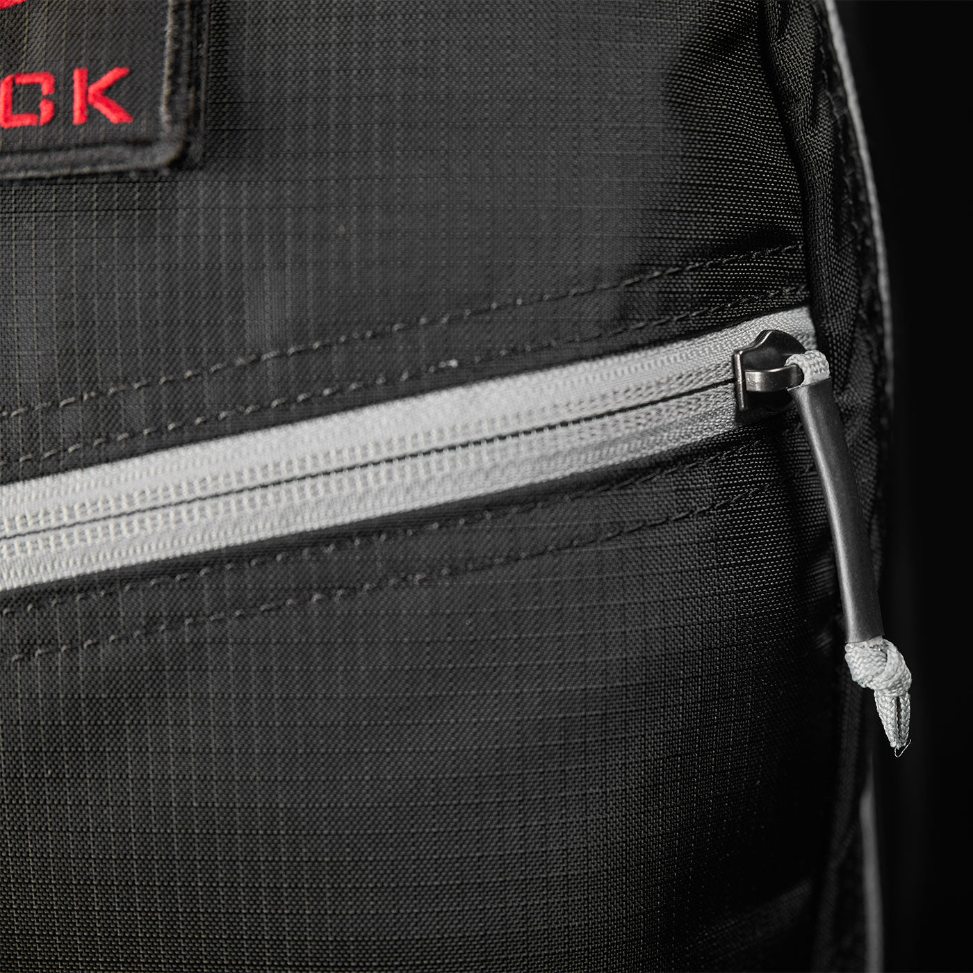 Close-up of a black fabric bag with a gray zipper and a knotted pull cord.