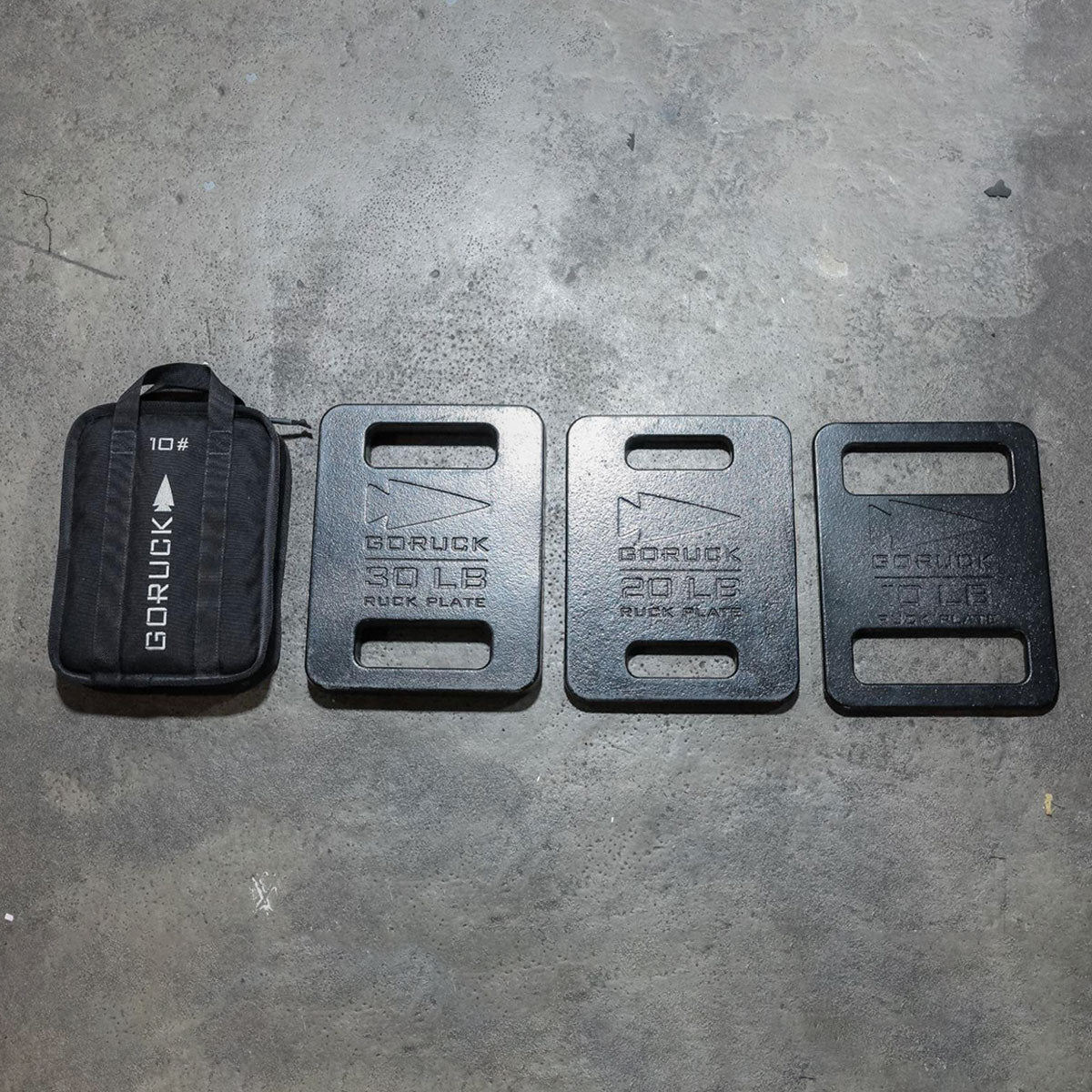 Four weighted ruck plates and a black GORUCK bag labeled 