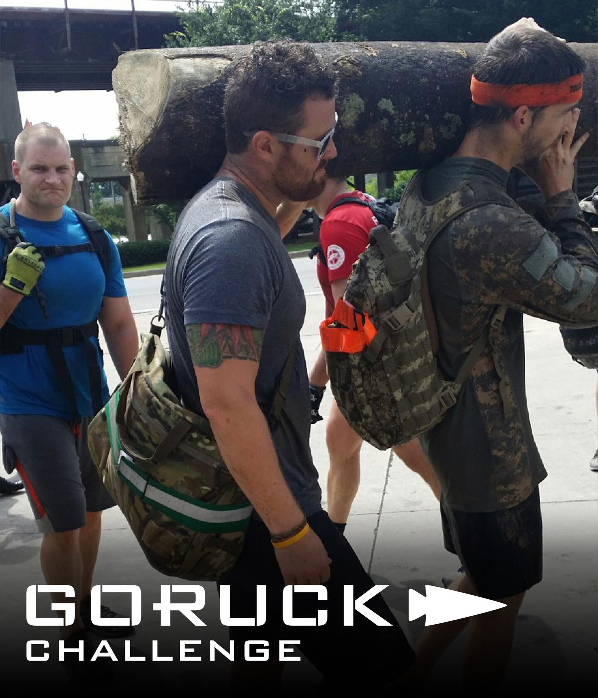 Four men carry a large log together outdoors; text at bottom reads 