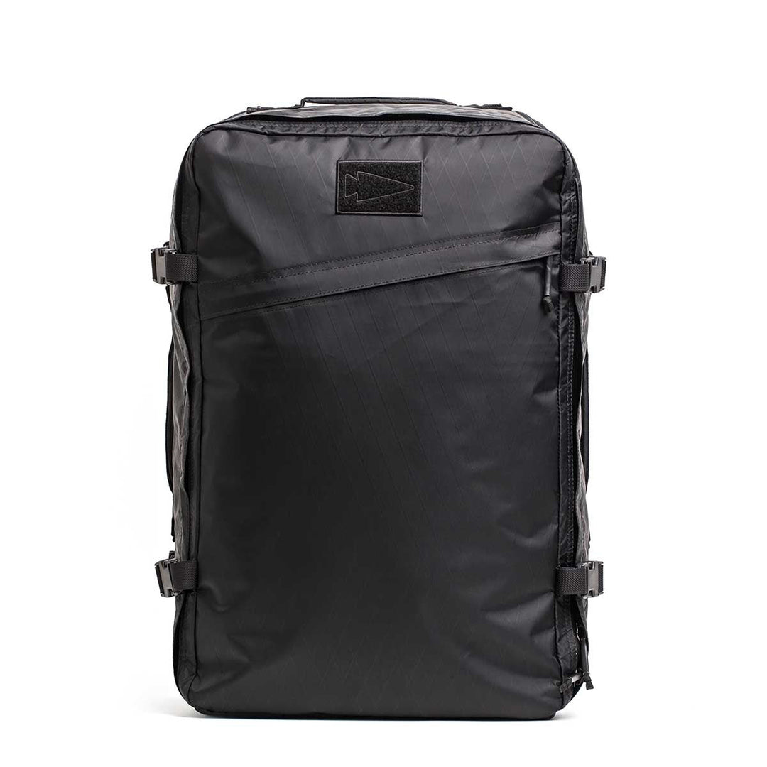 The GORUCK GR3 - X-PAC is a black rectangular carry-on backpack with a front diagonal zipper and side buckles, made from ultra-waterproof material, shown standing upright against a white background.